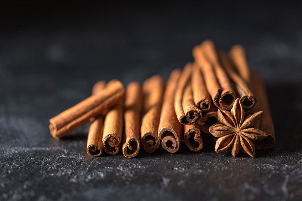 Des bâtons de cannelle et de l’anis étoilé sur une surface sombre.